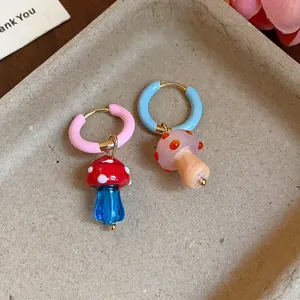 Close-up of asymmetric mushroom earrings with vibrant colorful glaze details