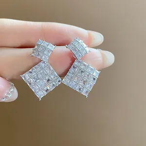 Primo piano di orecchini a rombo geometrici con brillanti pietre di zirconia cubica