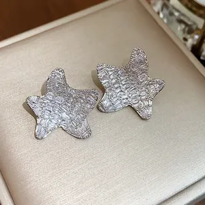 Close-up of sparkling star stud earrings with baguette-cut zircons on a jewelry box