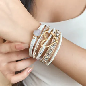Detail view of multi-layer white leather bracelet with gold heart and druzy stone