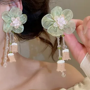 Close-up detail of resort style glass beaded flower tassel earrings with green fabric petals