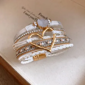 Close-up of elegant multilayer white leather bracelet with gold heart and druzy stone
