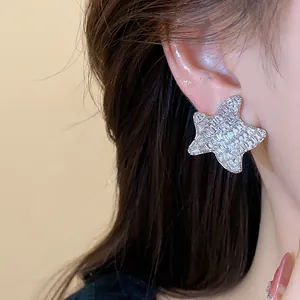 Close-up detail of shimmering zircon-studded star shaped stud earring worn on ear
