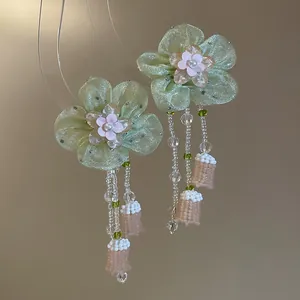Detailed view of handmade translucent flower earrings with long beaded tassels.