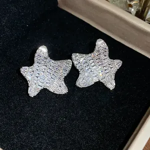 Close-up of sparkling star-shaped earrings with baguette-cut zircons on black velvet