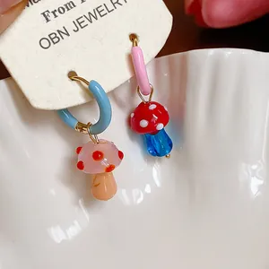 Detail of handmade glazed glass mushroom asymmetrical hoop earrings with colorful accents