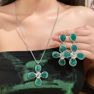 Close-up of green resin flower necklace and matching waterdrop earrings on model