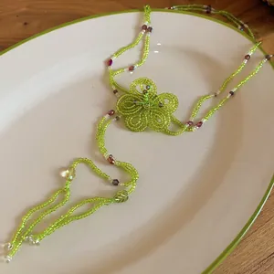 Close-up detail of vacation style green glass beaded flower necklace with tassels