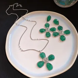 Detailed view of green resin flower necklace and earrings set on a white ceramic plate.