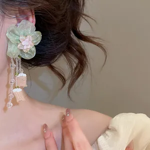 Detailed view of elegant green glaze beaded flower tassel earrings worn by a model