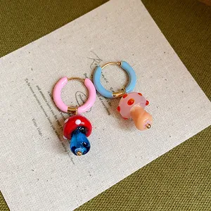 Macro detail of unique asymmetric mushroom hoop earrings with vibrant colorful glass charms