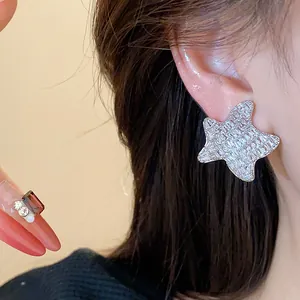 Detailed close-up showing sparkling star-shaped zircon stud earrings worn on a woman's ear