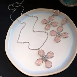 Detail view of pink resin flower necklace and earring jewelry set on a white plate