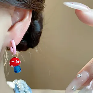 Macro view of a cute red mushroom earring with blue glass stem worn on an Asian ear