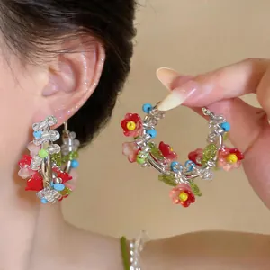 Close-up detail of colorful beaded flower hoop earrings featuring delicate floral patterns