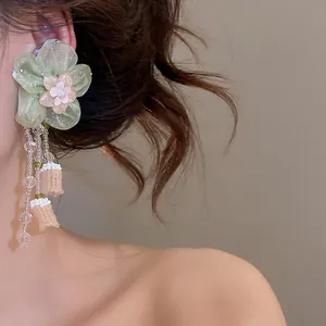 Detailed view of handmade green floral tassel earring with glass beads and woven accents