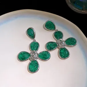 Detailed view of green resin flower earrings with silver-tone metal accents on a plate.