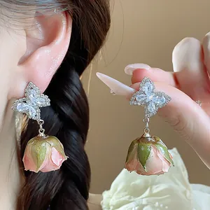 Detailed macro shot of zircon butterfly earrings with real preserved pink rose buds