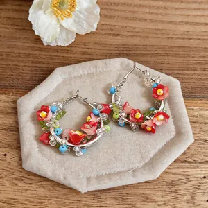 Detail view of ethnic handmade beaded flower hoop earrings on wooden rustic background