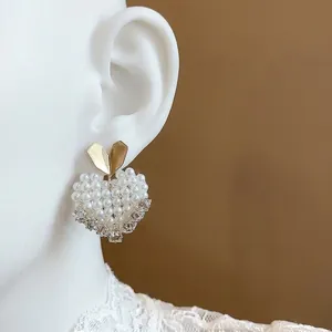 Elegant model wearing 14k gold plated heart pearl stud earrings with a luxury look