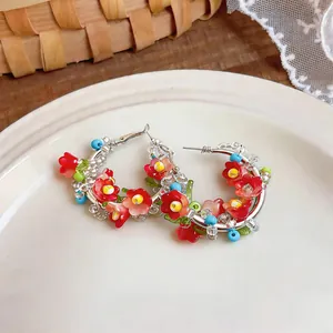 Detailed view of ethnic style hoop earrings featuring colorful beads and handmade red flowers.