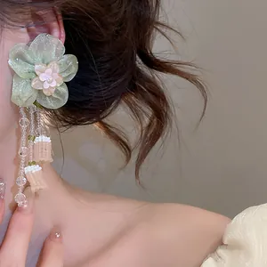 Close-up detail of elegant green glass bead flower tassel earrings worn by a model