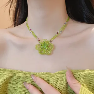 Macro detail view of handmade green glass beaded necklace featuring a large woven flower pendant.