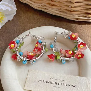 Close-up of ethnic style hoop earrings with colorful beads and red flowers on a plate