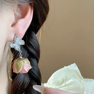 Detail of butterfly zircon earrings with pink preserved flower rosebud pendant