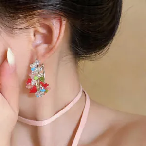 Detailed close-up view of ethnic colorful beaded flower hoop earrings worn by a model