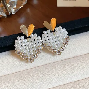 Close-up of elegant heart-shaped stud earrings featuring small white pearls and gold accents.