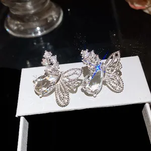 Gros plan de boucles d'oreilles papillon avec zircons gouttes et détails d'ailes évidées.