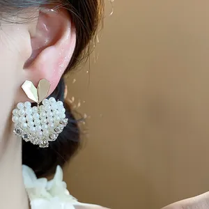 Detailed close-up of French style heart-shaped pearl stud earrings with 14k gold plating