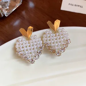 Detailed view of 14k gold plated heart-shaped pearl and crystal stud earrings