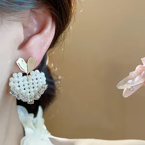 Close-up view of elegant heart-shaped pearl stud earring on a female model's ear