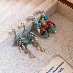Elegant vintage pearl and colorful stone dangle earrings displayed in a cream jewelry box