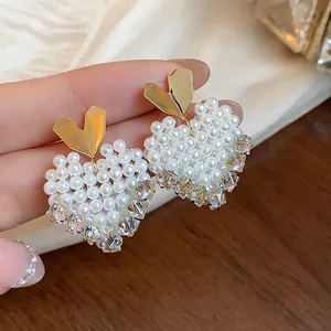 Detailed close-up of 14k gold plated heart-shaped earrings with pearls and crystals