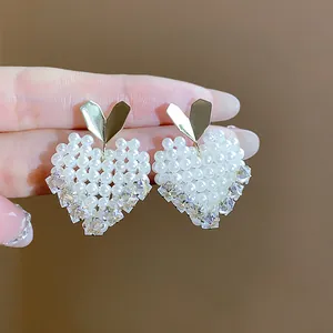 Close-up of elegant heart-shaped earrings featuring white pearls and sparkling crystals.
