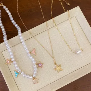 Detailed view of white pearl and gold necklaces with enamel starfish and shell pendants