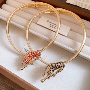 Macro detail of gold leopard choker necklace with red and black enamel spots.
