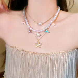 Close-up of pearl necklace featuring enamel starfish, mermaid tail and seashell charms.