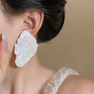 Detailed close-up showing texture of oversized white enamel leaf-shaped fashion earring