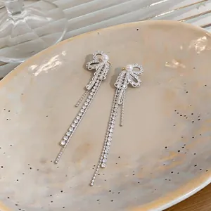 Close-up view of elegant silver bow tassel earrings with zircons and white pearls