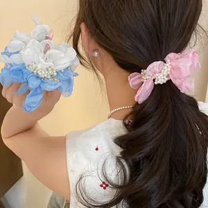 Detailed view of sweet chiffon flower scrunchies with pearls worn on wavy hair.