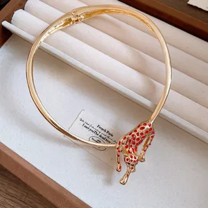 Detail view of a gold-toned leopard choker with vibrant red enamel spots in a box