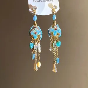 Close-up detail of vintage style drop earrings featuring light blue stones and golden accents