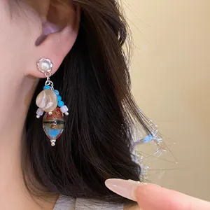 Detailed view of vintage-inspired pearl and colorful stone bead dangle earring worn on ear