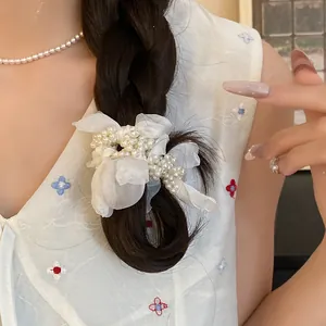 Close-up of a white chiffon flower hair tie with elegant pearls on a dark braid
