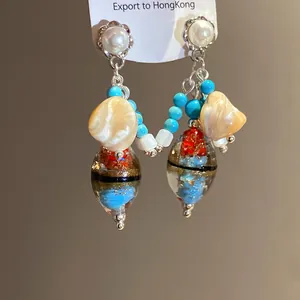 Close-up detail of vintage-style drop earrings with pearls and turquoise beads