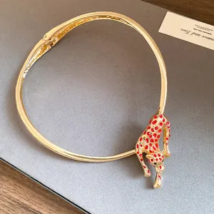 Macro view showing the intricate red enameled leopard detail on a gold metal choker necklace